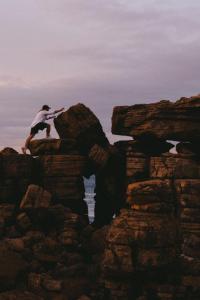 un hombre está saltando de algunas rocas en Guesthouse Beach Break en Peniche