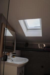a skylight in a bathroom with a sink and a mirror at Kula Apartman 3 in Brčko