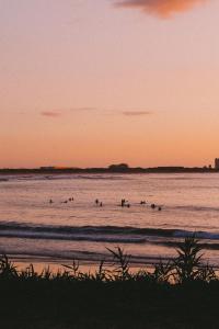 a group of people surfing in the ocean at sunset at Guesthouse Beach Break in Peniche