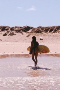 a person walking into the water with a surfboard at Guesthouse Beach Break in Peniche