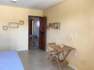 a bedroom with a bed and a table and a desk at Flat aconchegante a uma quadra da praia in Trairi