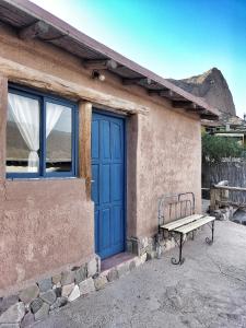 a bench sitting outside of a building with a blue door at El Cerrito in Maimará +24 photos