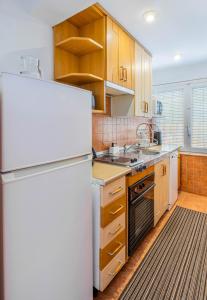 a kitchen with a white refrigerator and wooden cabinets at Bungalow Calpe con Piscina, Tenis, Parking in Calpe