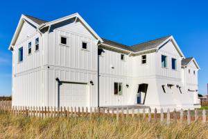 a white house with a fence in a field at Scenic Bandon Vacation Rental with Beach Access! in Bandon