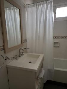baño blanco con lavabo y ventana en Departamento Caseros en Salta