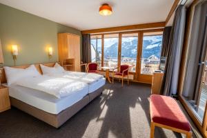 um quarto de hotel com uma cama, uma mesa e cadeiras em Hotel Jungfraublick em Wengen