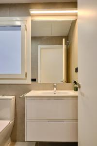 a white bathroom with a sink and a mirror at Apartamento La Perla Little Apartments in Cádiz