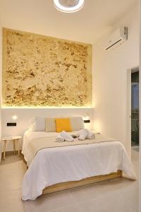 a bedroom with a large white bed with a yellow pillow at Apartamento La Perla Little Apartments in Cádiz