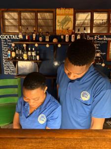 two men in blue shirts standing at a bar at Kameleon Blue in Kizimkazi