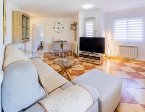 a living room with a couch and a flat screen tv at Bungalow Calpe con Piscina, Tenis, Parking in Calpe