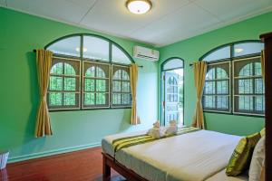 - une chambre avec des murs verts et un lit avec des fenêtres dans l'établissement Bann Mangkud Khaolak, à Khao Lak