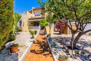a house with a tree and a sidewalk at Bungalow Calpe con Piscina, Tenis, Parking in Calpe