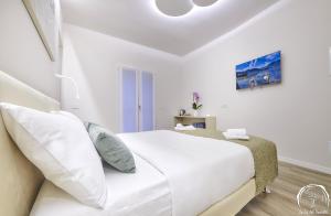 a white bedroom with a large bed with white pillows at FORESTERIA GUESTHOUSE CA' DEI BACHITT in Lierna