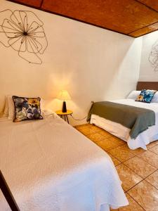 Orquídea Loft في Juayúa: غرفة نوم فيها سريرين ومصباح