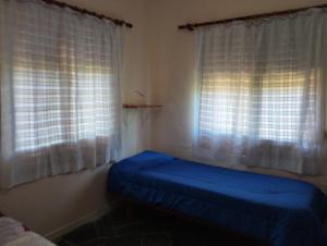 1 dormitorio con 1 cama azul y 2 ventanas en Casa Vacacional MIA, en Piriápolis