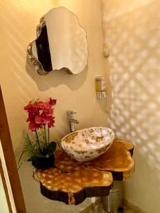 baño con lavabo y jarrón con flores rojas en Orquídea Loft, en Juayúa