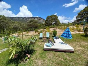 - un lit dans l'herbe avec 2 chaises et un parasol dans l'établissement Casa Rustica na Chapada Diamantina - Recanto Morro do Sobrado, à João Pessoa