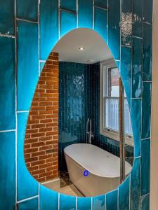 a blue tiled bathroom with a tub and a mirror at The Castle City Centre Apartment in Canterbury