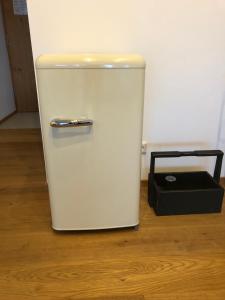 a white refrigerator and a black box on a wooden floor at Klosterblick - Inzigkofen (FeWo mit Naturteich) in Inzigkofen