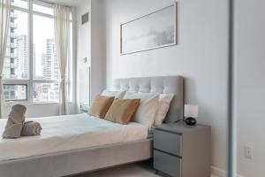 a white bedroom with a bed with a window at Fort York Apartments in Toronto