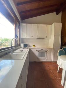 cocina con armarios blancos, fregadero y ventana en Casa do Lagar, 