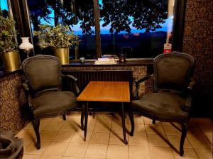 twee stoelen en een houten tafel voor een raam bij Hammenhögs gästgivaregård in Hammenhög