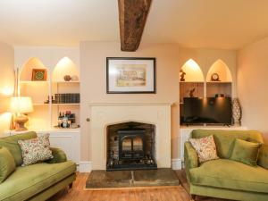 a living room with two green couches and a fireplace at Reybridge House in Chippenham