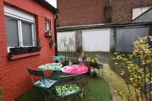 eine Terrasse mit einem Tisch und Stühlen neben einem Gebäude in der Unterkunft Maison cosy dans le centre ville de Lens in Lens