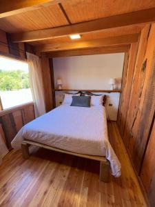 1 dormitorio con 1 cama en una habitación de madera en Kumewe Lodge en Panguipulli