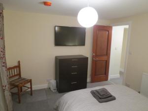 1 dormitorio con 1 cama y TV en la pared en The Heritage Guest House, en Montrose