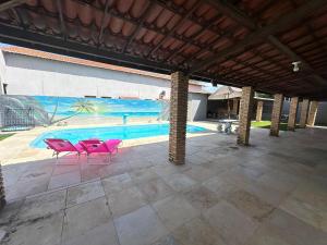 un patio con sillas rosas y una piscina en Casa de Praia em Morro Branco-CE en Beberibe