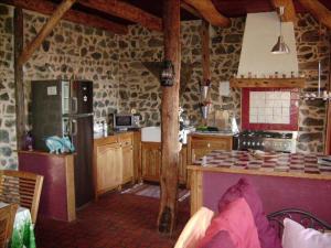 a kitchen with stone walls and a kitchen with a refrigerator at Maison de charme au coeur du Sancy en Auvergne in Saurier