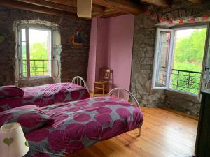 two beds in a room with pink walls and windows at Maison de charme au coeur du Sancy en Auvergne in Saurier