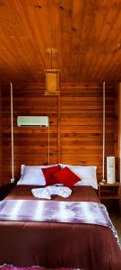 a bedroom with a bed with red and white pillows at Pousada Floresta Das Estrelas in Urubici