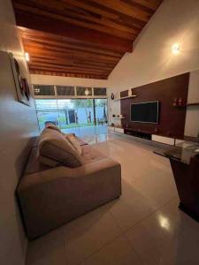 Il comprend un grand salon avec un canapé et une télévision. dans l'établissement Residencial Bem-te-vi, à Matão