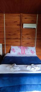 a bed with blue sheets and pink flowers on it at Pousada Floresta Das Estrelas in Urubici