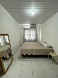 1 dormitorio con cama, espejo y ventana en Apartamento em Porto Belo, en Porto Belo