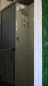 ducha con puerta de cristal y cabezal de ducha en Chalé Mar a Vista Conforto e Pé na areia, en Arroio do Silva