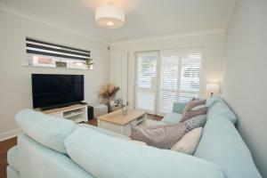 a living room with a blue couch and a tv at Chine Wood Retreat - Walk to the beach and the lovely Westbourne - Free parking in Bournemouth