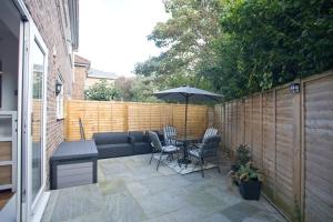a patio with a table and chairs and an umbrella at Chine Wood Retreat - Walk to the beach and the lovely Westbourne - Free parking in Bournemouth
