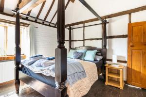 ein Schlafzimmer mit einem Himmelbett mit blauen Kissen in der Unterkunft Beautiful 17th Century Cottage in Buckinghamshire