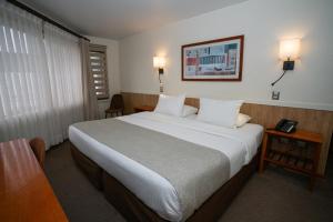 a hotel room with a large bed and a telephone at Hotel Don Luis Puerto Montt in Puerto Montt