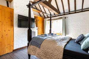 ein Schlafzimmer mit einem Bett und einem Flachbildfernseher in der Unterkunft Beautiful 17th Century Cottage in Buckinghamshire