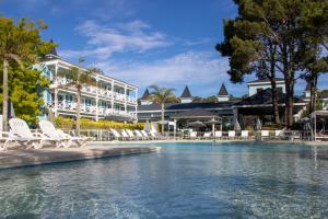 una piscina en un complejo con sillas y un edificio en Howard Johnson Hotel & Convention Center Madariaga - Carilo en Cariló
