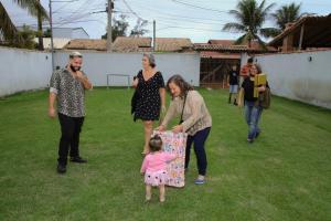 un grupo de personas de pie alrededor de una niña sosteniendo una bolsa en espaço 16, en Maricá