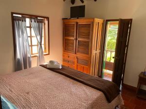 a bedroom with a bed and a dresser and a window at Hostal El Pino in Villa de Leyva