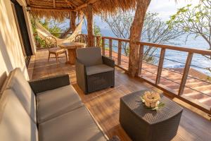 a porch with chairs and a table and a view of the ocean at Paraiso Escondido Hotel Villas & Resort in El Níspero