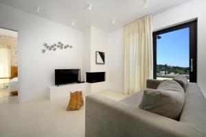 a living room with a couch and a tv at Mega Lithari Corfu Luxury Villas in Kavvadádes