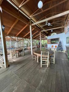 una terraza cubierta con mesas y sillas de madera. en Hotel Ecológico Cabañas del Lago, en El Estor