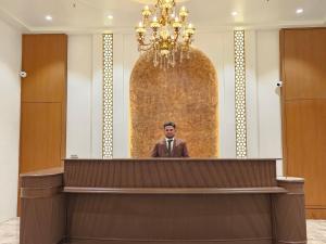 Een man in een pak die achter een podium staat. bij Hotel The S Crown in Somnath